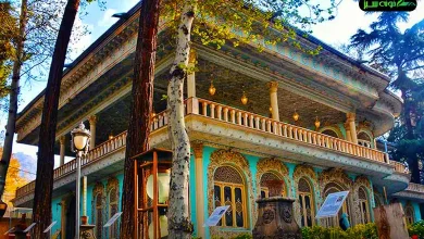 نمای بیرونی عمارت موزه زمان با معماری قاجاری، درختان بلند و نورپردازی گرم